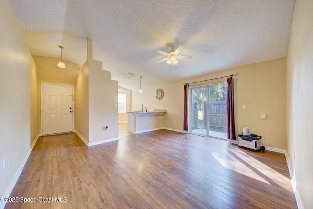 unfurnished living room featuring lofted ceiling, a textured ceiling, light hardwood / wood-style flooring, and ceiling fan