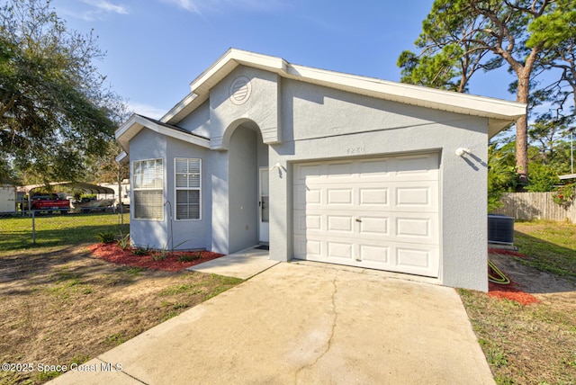 single story home featuring central AC unit and a garage