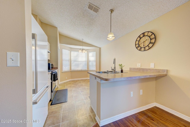 kitchen with lofted ceiling, sink, hanging light fixtures, kitchen peninsula, and stainless steel appliances