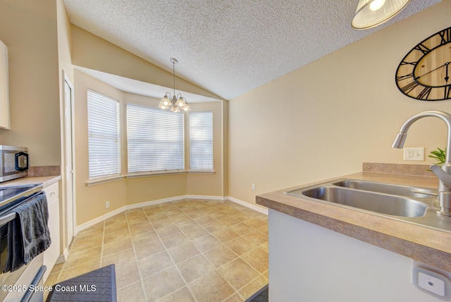 kitchen with lofted ceiling, sink, decorative light fixtures, a textured ceiling, and stainless steel appliances