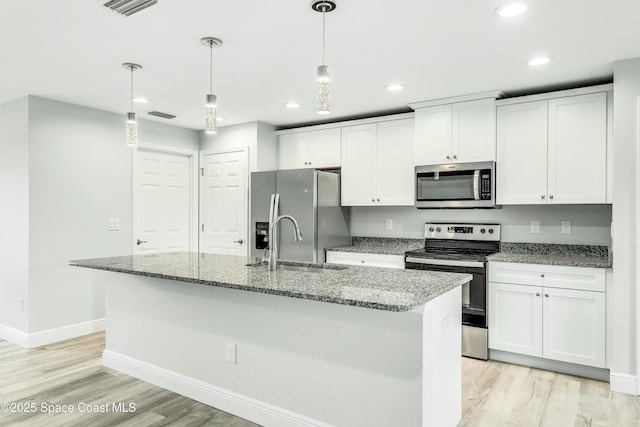 kitchen with decorative light fixtures, stainless steel appliances, an island with sink, and white cabinets