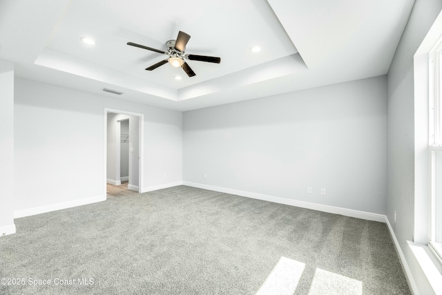 carpeted empty room with ceiling fan and a raised ceiling