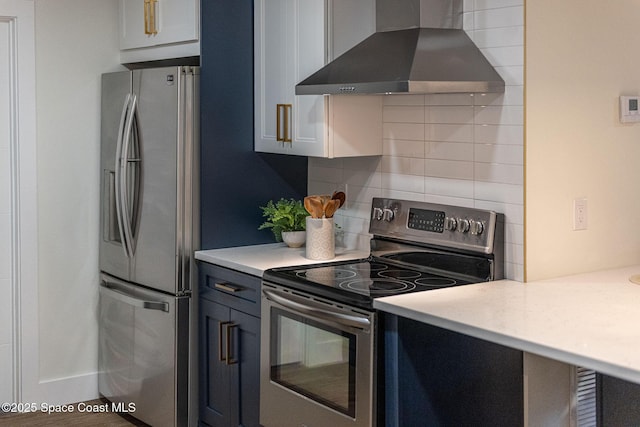 kitchen with tasteful backsplash, stainless steel appliances, blue cabinetry, and wall chimney range hood