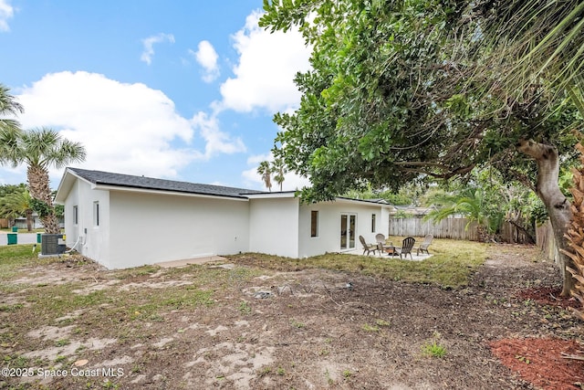 rear view of property featuring a patio, cooling unit, and an outdoor fire pit