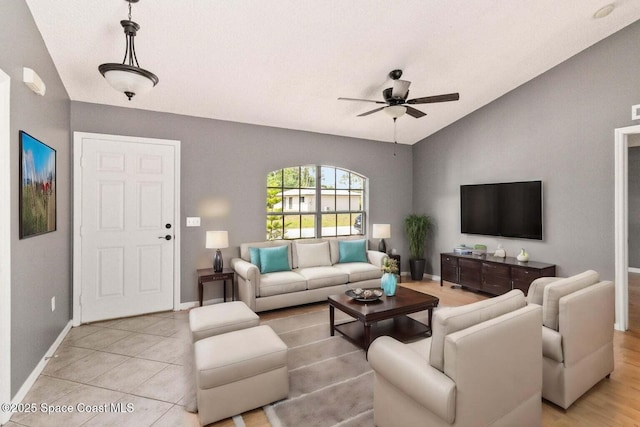 living room with lofted ceiling, ceiling fan, and light tile patterned flooring