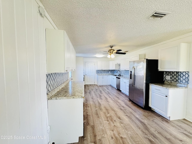 kitchen featuring sink, ceiling fan, appliances with stainless steel finishes, white cabinetry, and light wood-type flooring