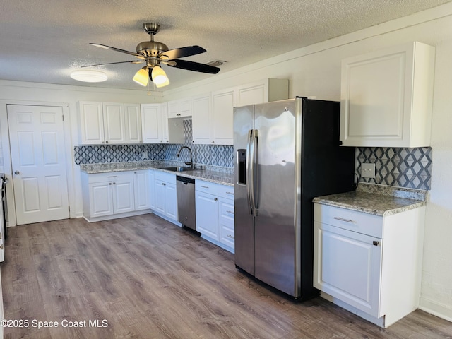 kitchen featuring sink, light hardwood / wood-style flooring, appliances with stainless steel finishes, white cabinetry, and backsplash