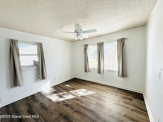 spare room featuring dark wood-type flooring, ceiling fan, and a textured ceiling