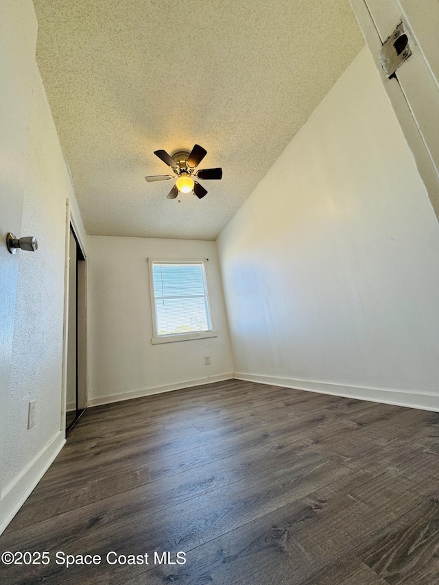 unfurnished room featuring dark wood-type flooring, ceiling fan, lofted ceiling, and a textured ceiling