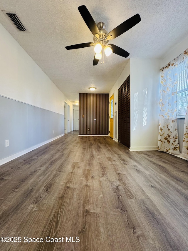 unfurnished room with ceiling fan, wood-type flooring, and a textured ceiling