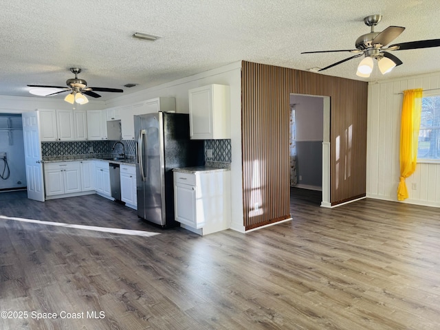 kitchen featuring appliances with stainless steel finishes, tasteful backsplash, white cabinets, dark hardwood / wood-style flooring, and a textured ceiling