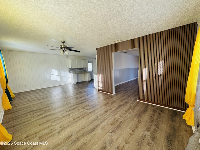 unfurnished living room featuring ceiling fan, wood-type flooring, and a textured ceiling