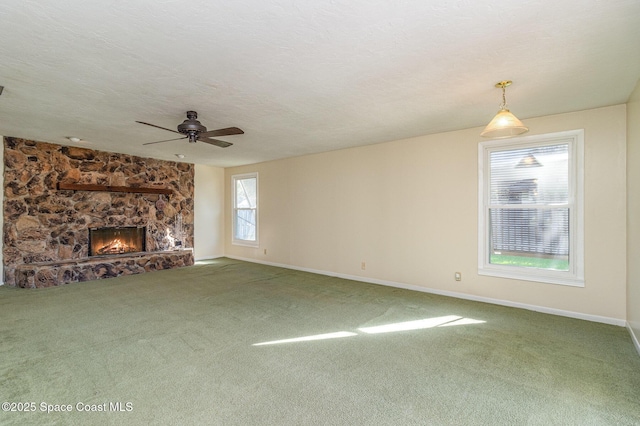 unfurnished living room featuring ceiling fan, carpet flooring, a textured ceiling, and a fireplace