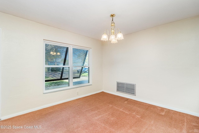 spare room featuring a chandelier and carpet