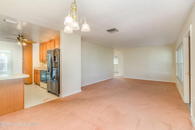 kitchen with stainless steel fridge, stove, hanging light fixtures, ceiling fan with notable chandelier, and light colored carpet