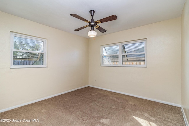 carpeted spare room featuring ceiling fan and a wealth of natural light