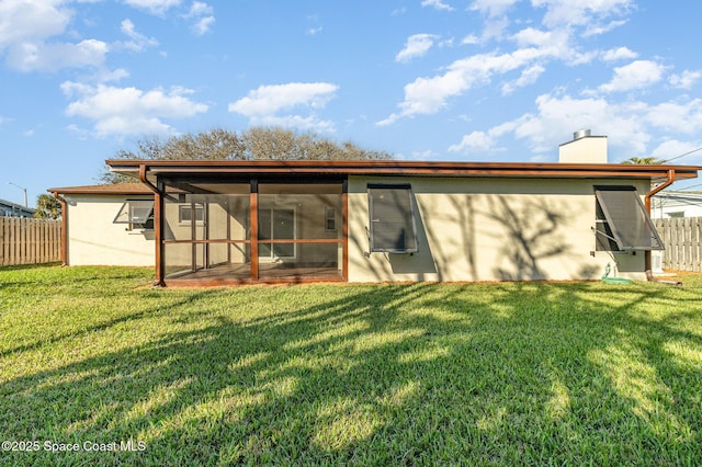 rear view of house with a yard and a sunroom