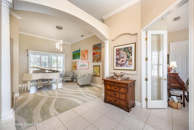 interior space featuring crown molding, light tile patterned flooring, and decorative columns