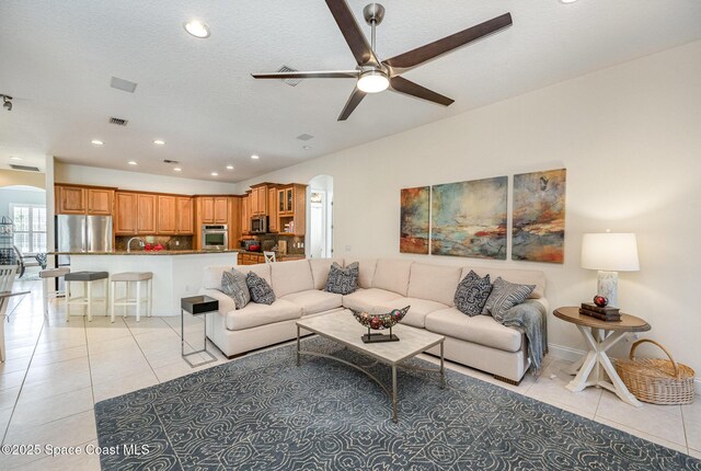 tiled living room featuring ceiling fan, sink, and a textured ceiling