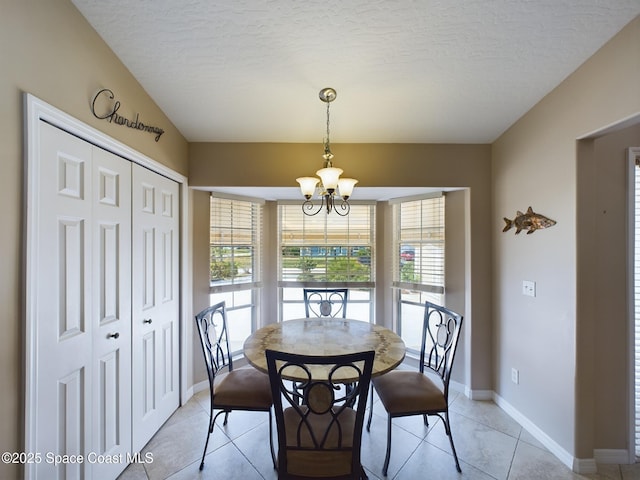 tiled dining room featuring a chandelier and a textured ceiling