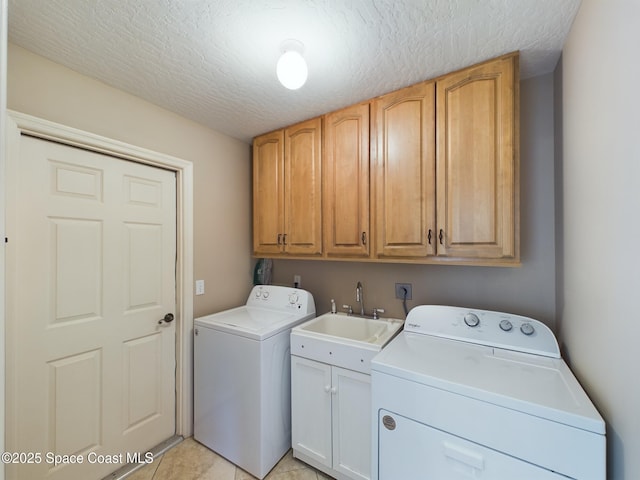 laundry room with cabinets, sink, a textured ceiling, and washing machine and clothes dryer