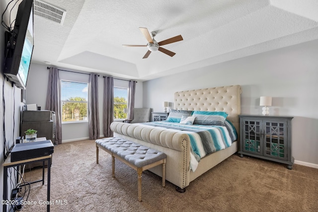 bedroom featuring ceiling fan, carpet, a textured ceiling, and a tray ceiling