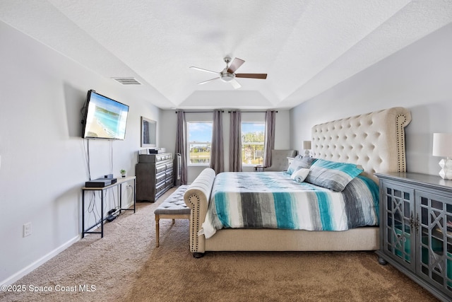 carpeted bedroom with ceiling fan, a tray ceiling, and a textured ceiling