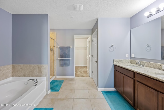 bathroom featuring tile patterned flooring, plus walk in shower, vanity, and a textured ceiling