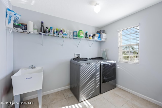 laundry area featuring light tile patterned flooring, sink, and washing machine and dryer