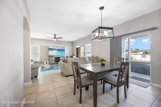 tiled dining room with ceiling fan with notable chandelier