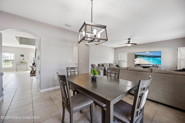 tiled dining area featuring ceiling fan with notable chandelier