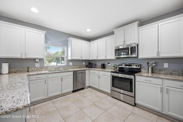 kitchen featuring light tile patterned flooring, white cabinetry, sink, light stone counters, and stainless steel appliances