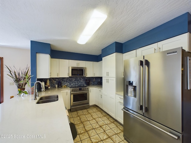 kitchen featuring sink, white cabinets, backsplash, stainless steel appliances, and a textured ceiling