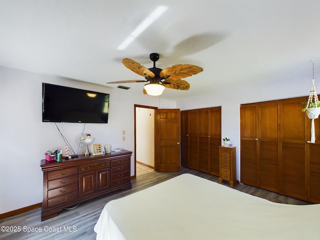 bedroom with multiple closets, ceiling fan, and wood-type flooring