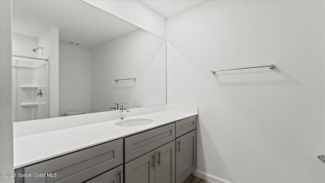 bathroom with a shower, vanity, and baseboards