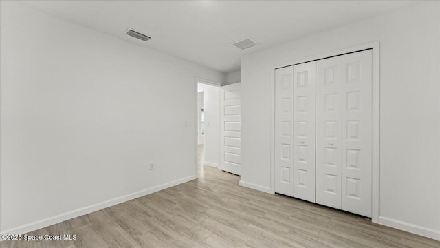 unfurnished bedroom featuring light wood-style flooring, a closet, visible vents, and baseboards