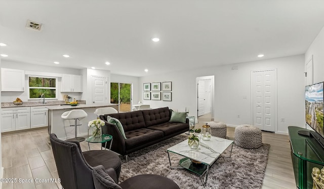 living room featuring light wood finished floors, visible vents, baseboards, and recessed lighting