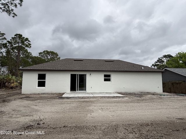 back of house with a shingled roof, a patio, fence, and stucco siding