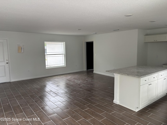 interior space featuring a textured ceiling, baseboards, and dark wood-type flooring