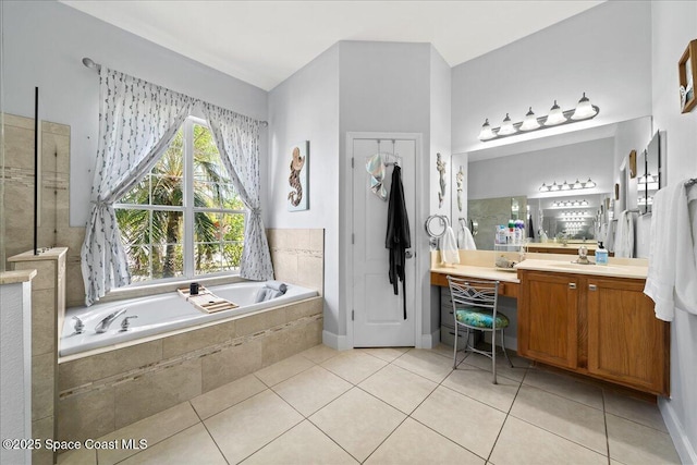 bathroom with tiled tub, vanity, and tile patterned flooring