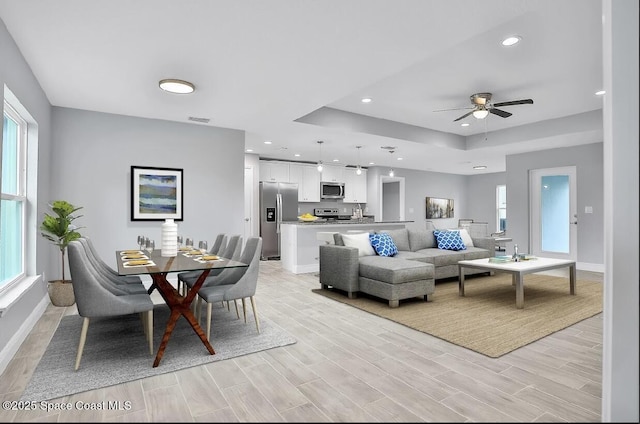 living room with ceiling fan and a tray ceiling