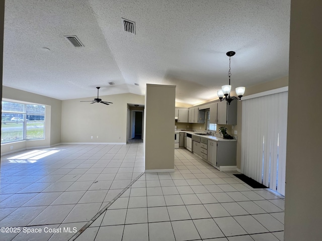 kitchen featuring light tile patterned flooring, lofted ceiling, sink, gray cabinetry, and ceiling fan with notable chandelier