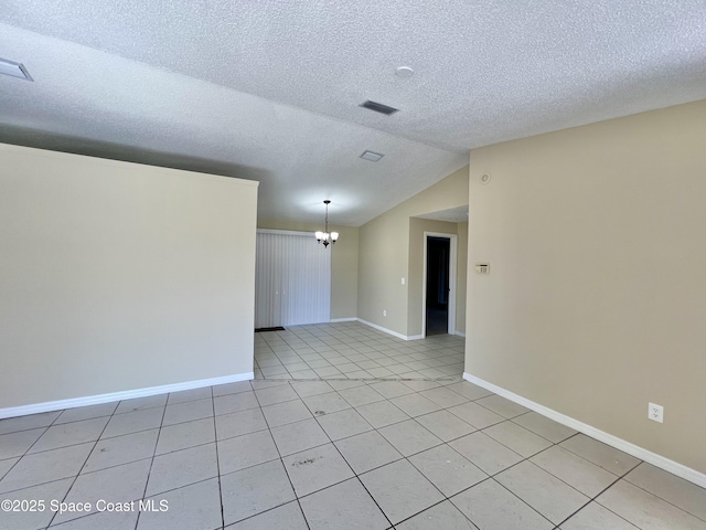 tiled spare room featuring a textured ceiling, vaulted ceiling, and a chandelier