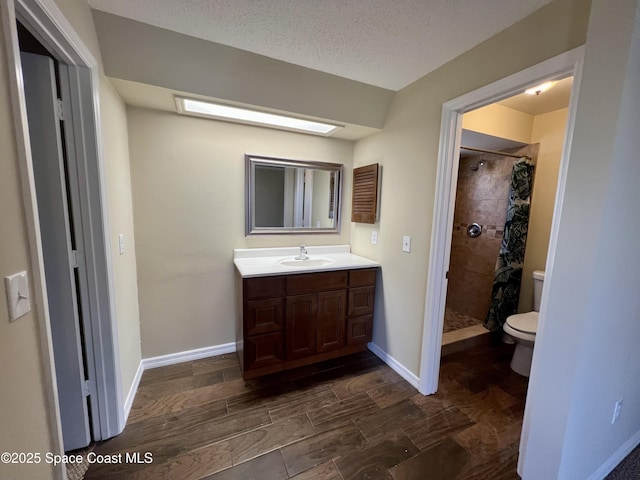 bathroom featuring vanity, toilet, curtained shower, and a textured ceiling