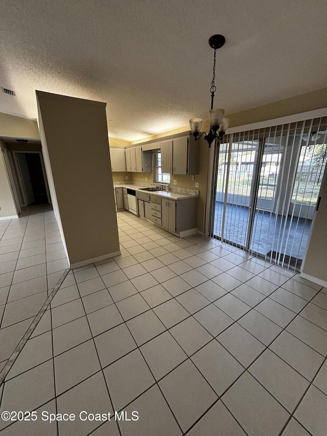 kitchen with light tile patterned floors, sink, a notable chandelier, a textured ceiling, and decorative light fixtures