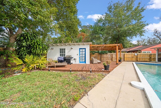 rear view of house featuring a wooden deck, a pergola, an outbuilding, and a lawn