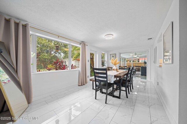 dining space featuring ceiling fan and a textured ceiling