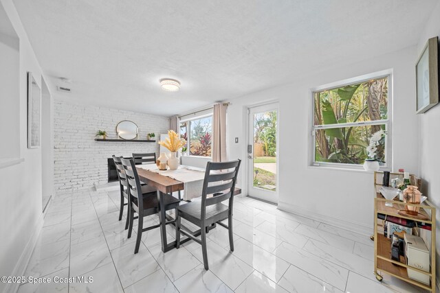 dining area featuring brick wall and a textured ceiling