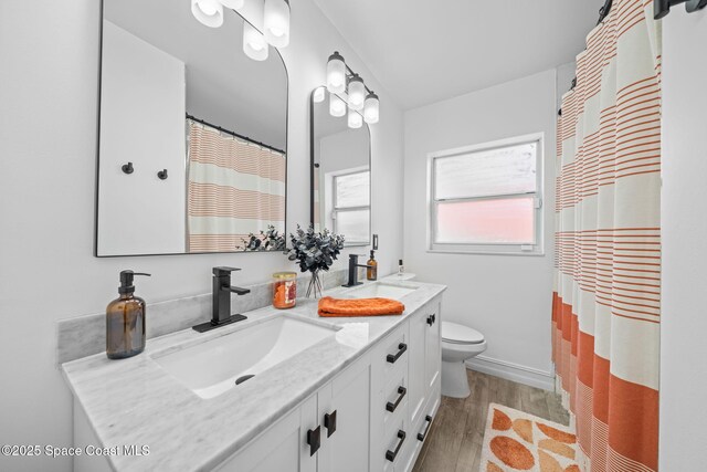 bathroom featuring wood-type flooring, toilet, curtained shower, and vanity