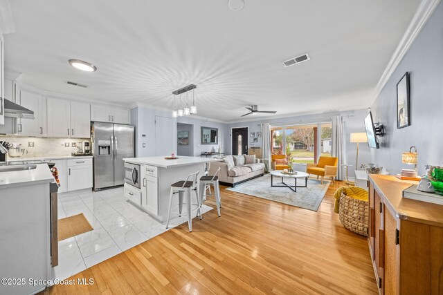 kitchen with stainless steel appliances, decorative light fixtures, a center island, and white cabinets